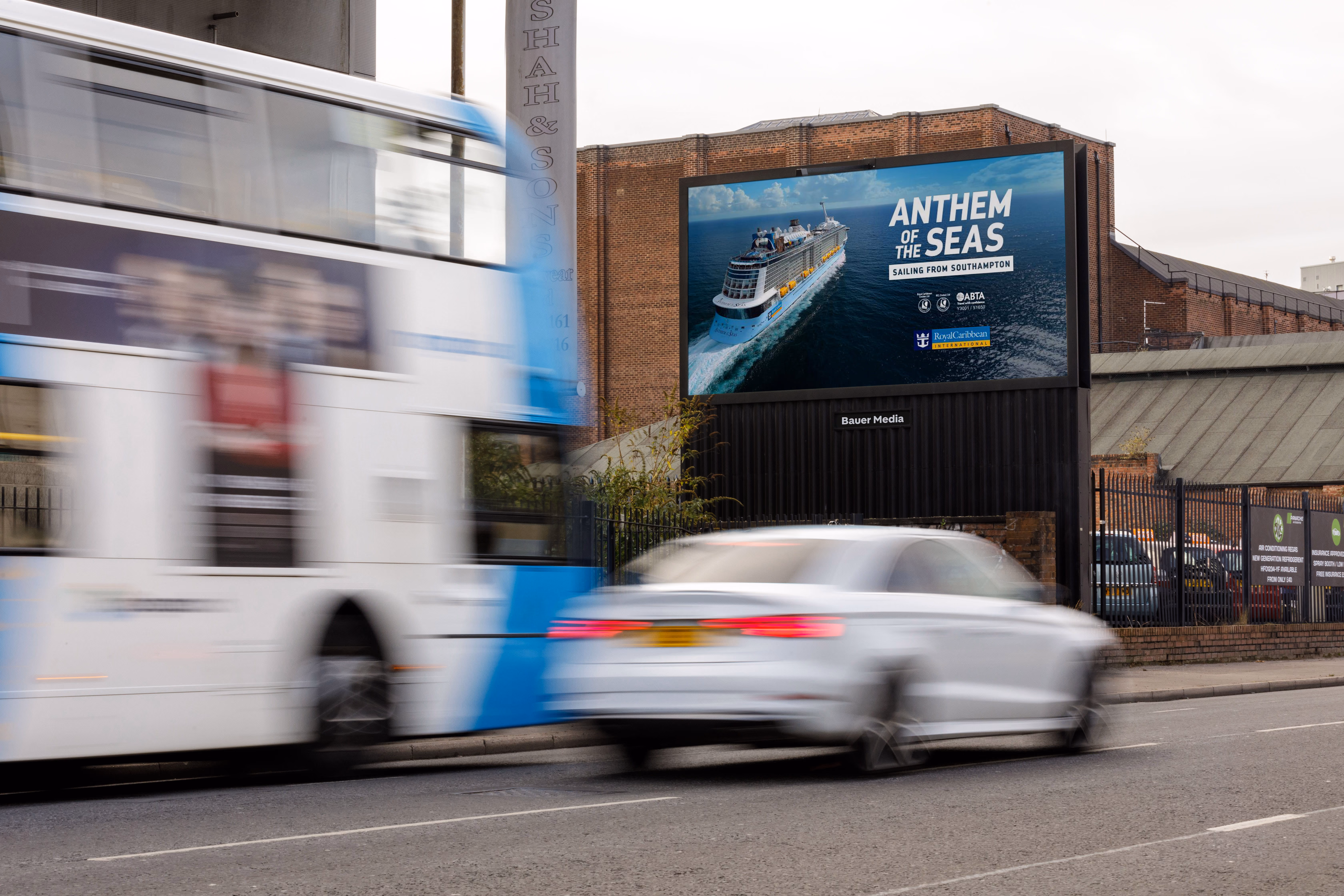 Digital billboard on brick building shows Royal Caribbean's Anthem of the Seas cruise ship ad.