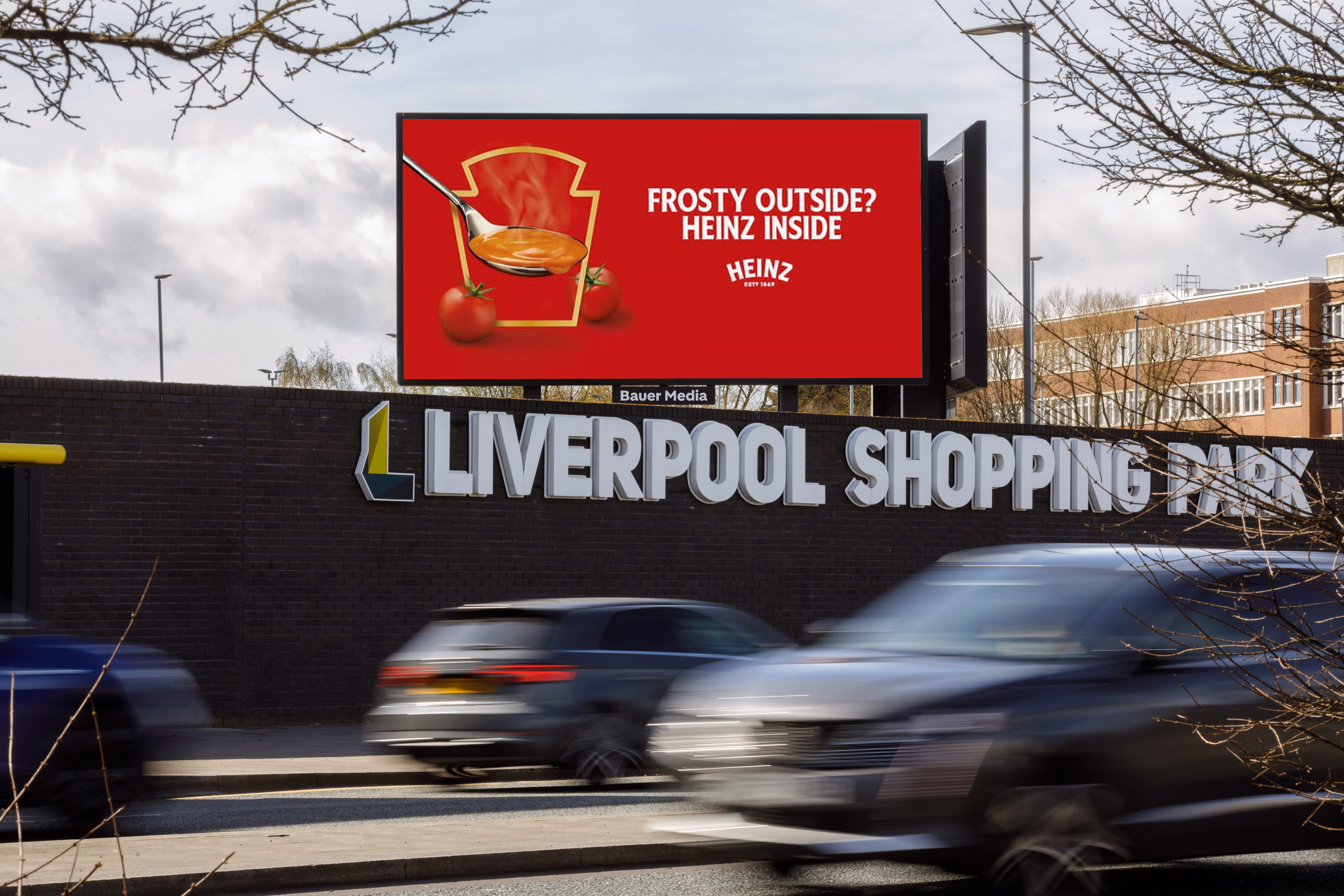 Billboard at Liverpool Shopping Park shows Heinz ad with spoon of soup and text 'Frosty outside? Heinz inside'.