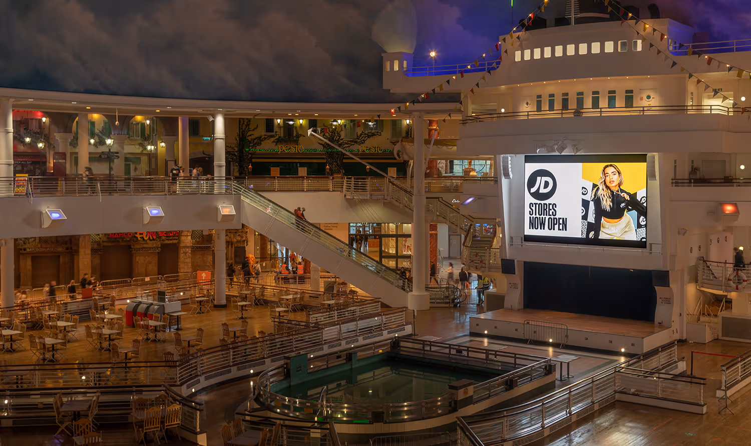 Large digital billboard in a shopping mall showing ad for JD Sports