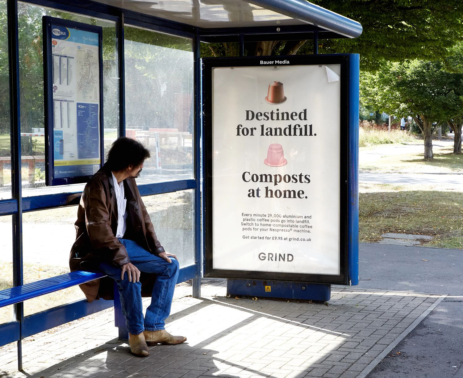 GRIND advertising on a bus stop poster with a person sat down reading the advert