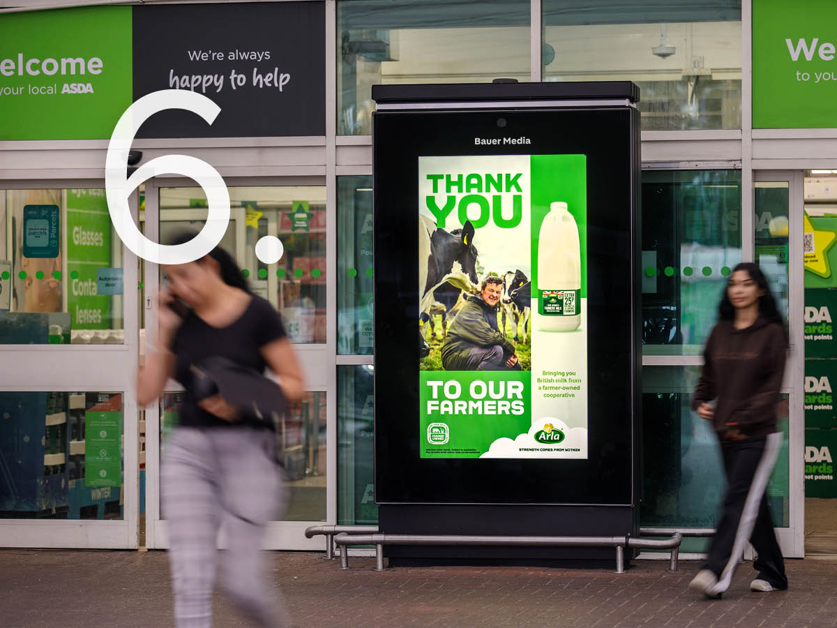 A Bauer Media digital screen outside an Asda store displaying an Arla 'Thank You to Our Farmers' milk advertisement, with pedestrians passing by.