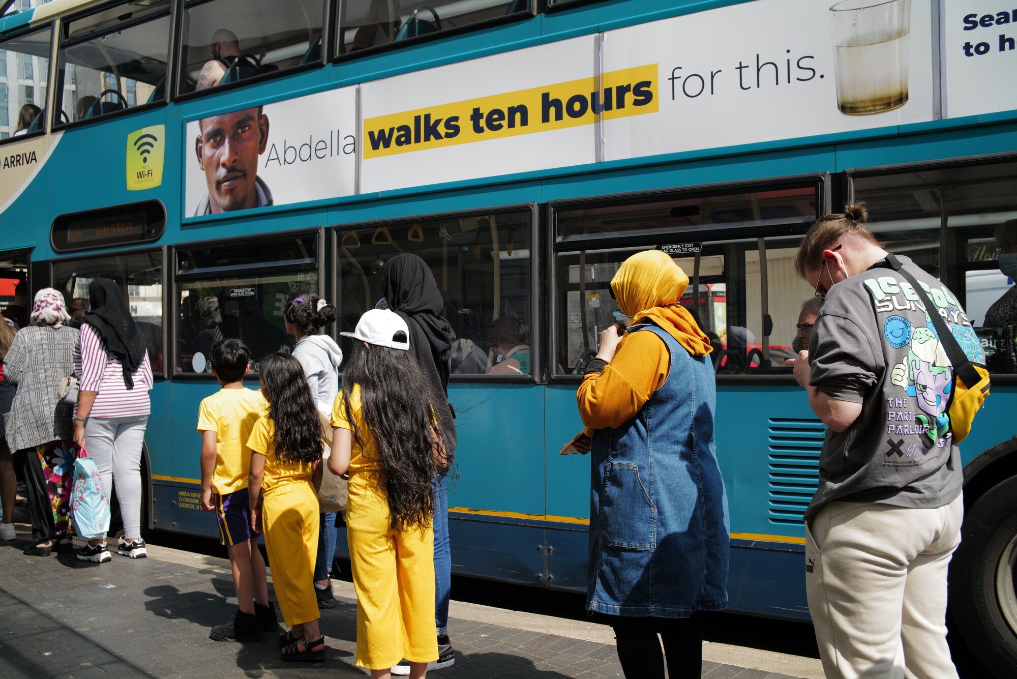 Passengers queue to board a bus
