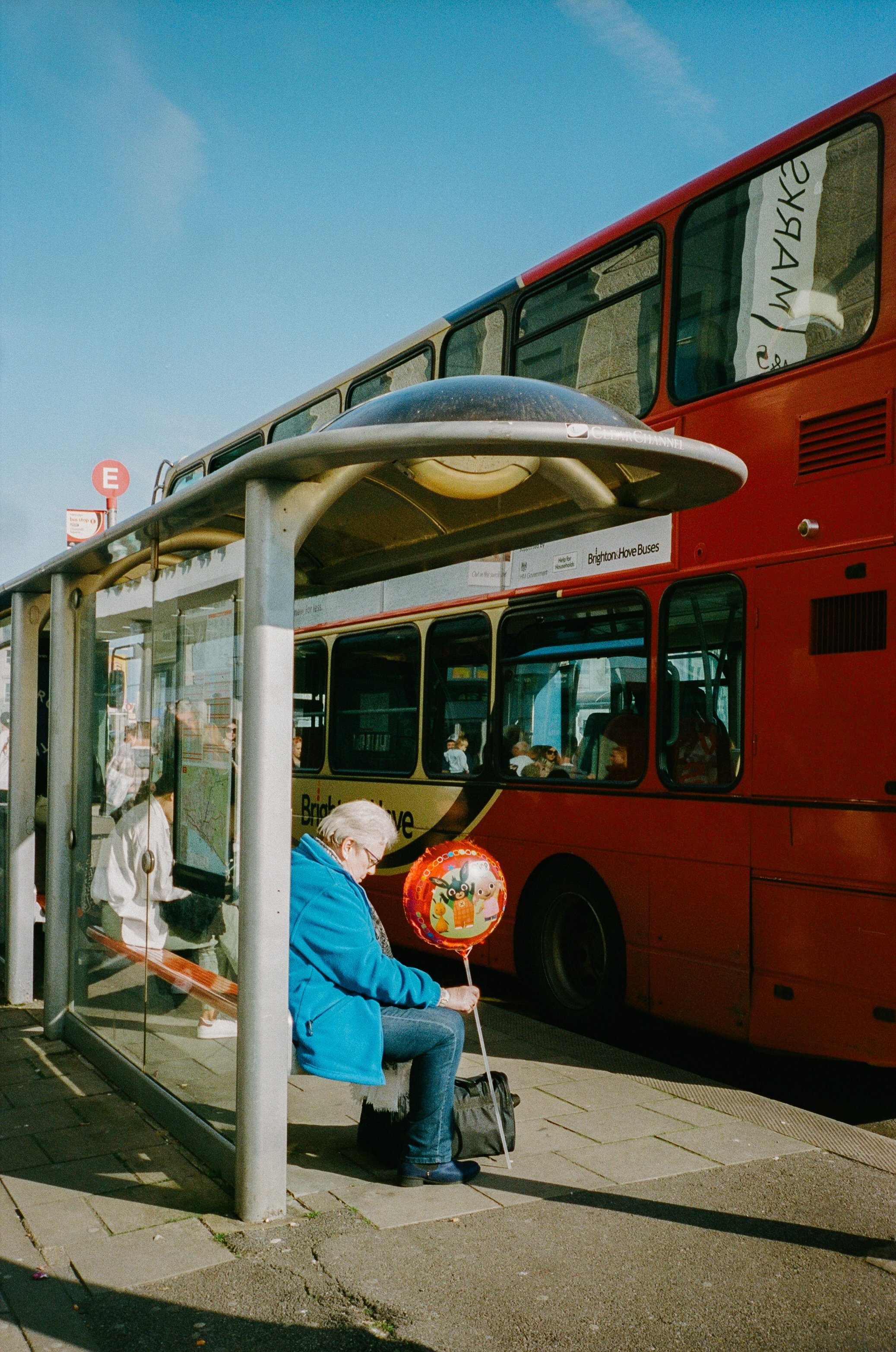 Woman waits in front of bus at bus stop with a balloon