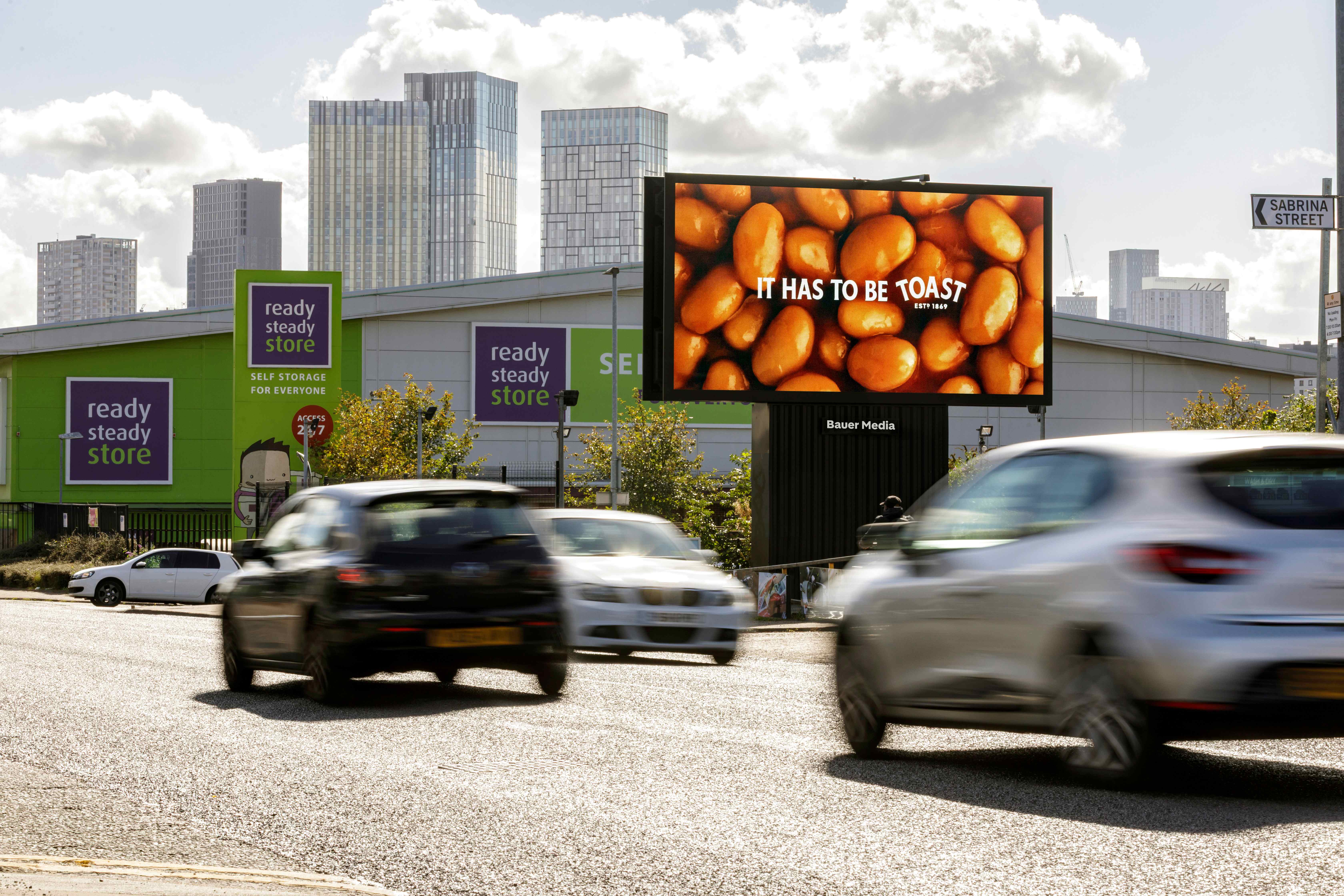 Billboard displaying Heinz "It has to be Toast" advertisement on a busy road.