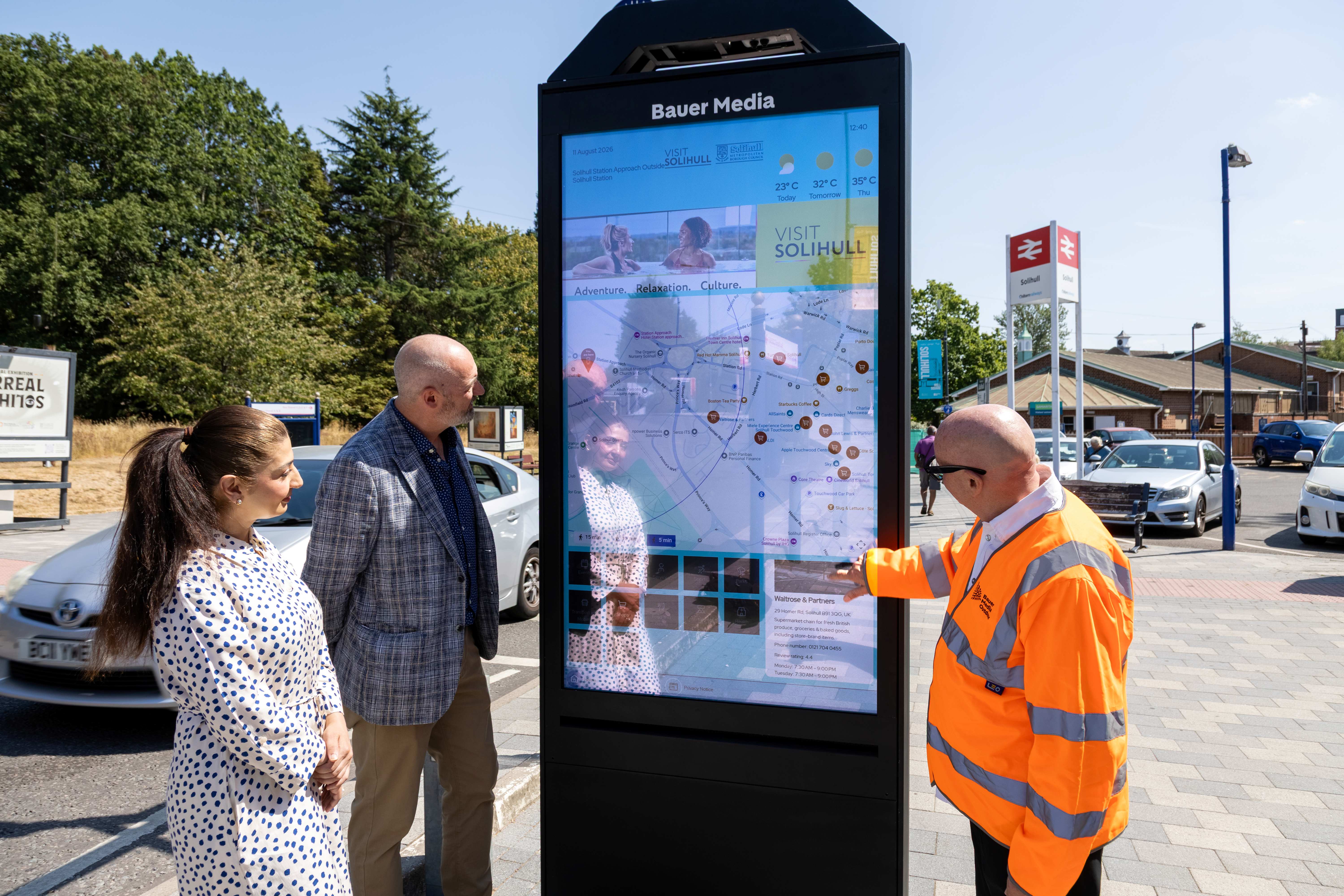 A Bauer Media Outdoor UK employee demonstrates using the newly installed Wayfinder in Solihul to local residents, during the day at Solihull Station.