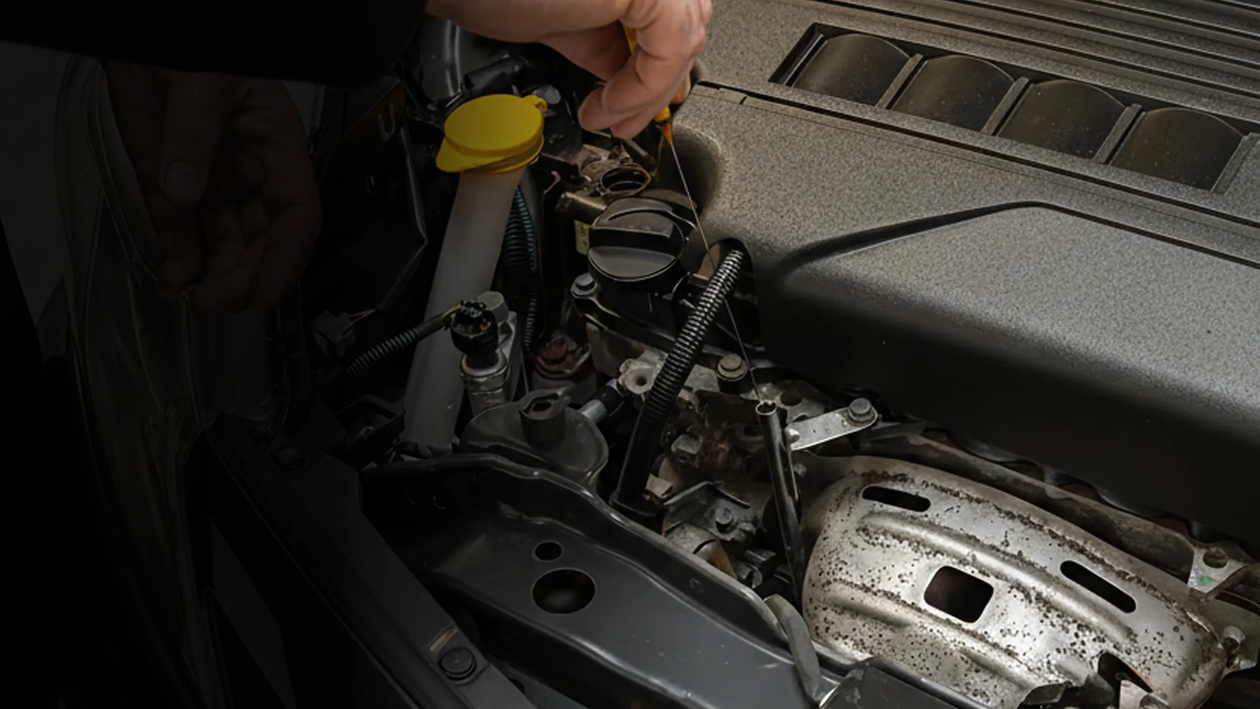 Close-up of a hand checking the engine oil level with a dipstick under a car's hood.