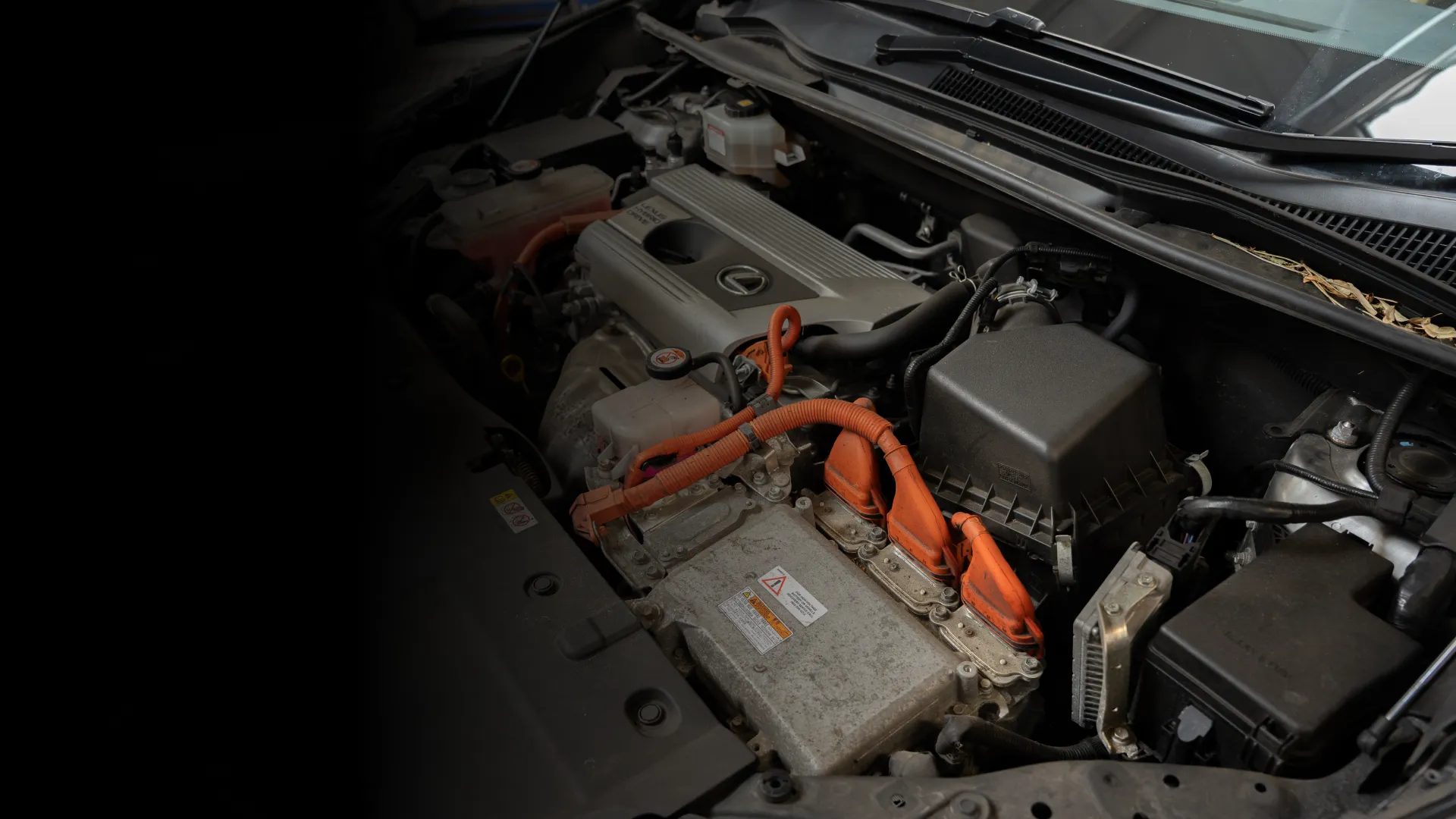 Close-up view of a Lexus hybrid car engine with orange high-voltage cables.