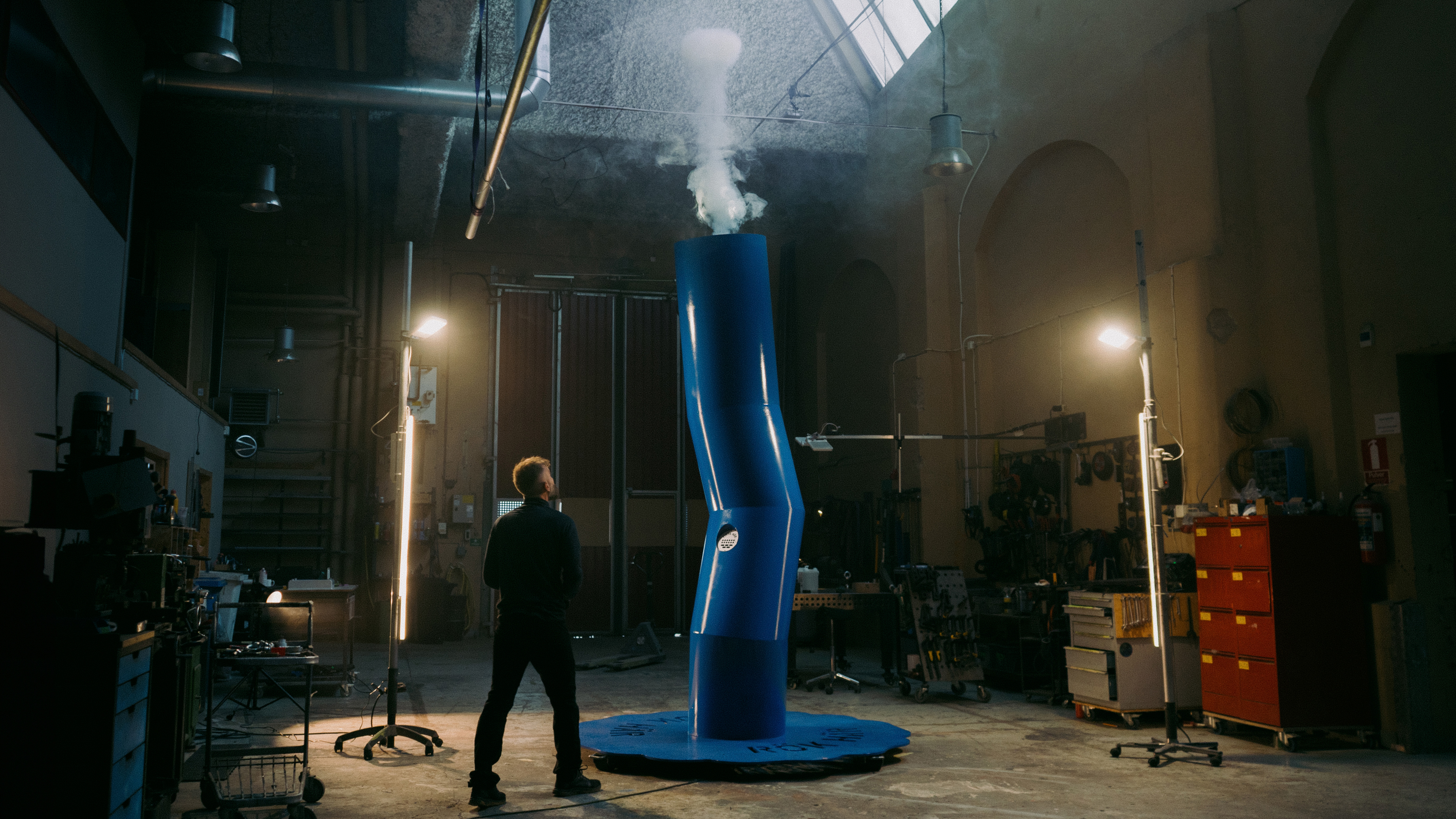 a person looking up at the smoke signals machine inside a workshop