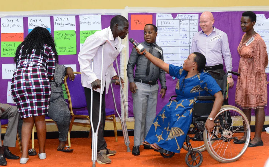 People with physical disabilities engaging in a group discussion with charts on the wall behind them.