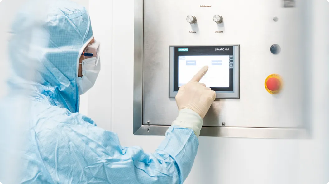 Arbeitende Person in Schutzkleidung bedient einen Siemens SIMATIC HMI Touchscreen an einer Edelstahlmaschine.