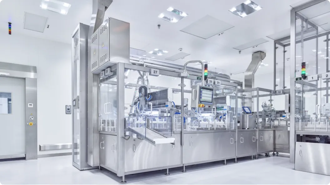 Moderne, sterile Produktionsstraße mit automatisierten Edelstahlmaschinen in einem weißen Reinraumlabor.