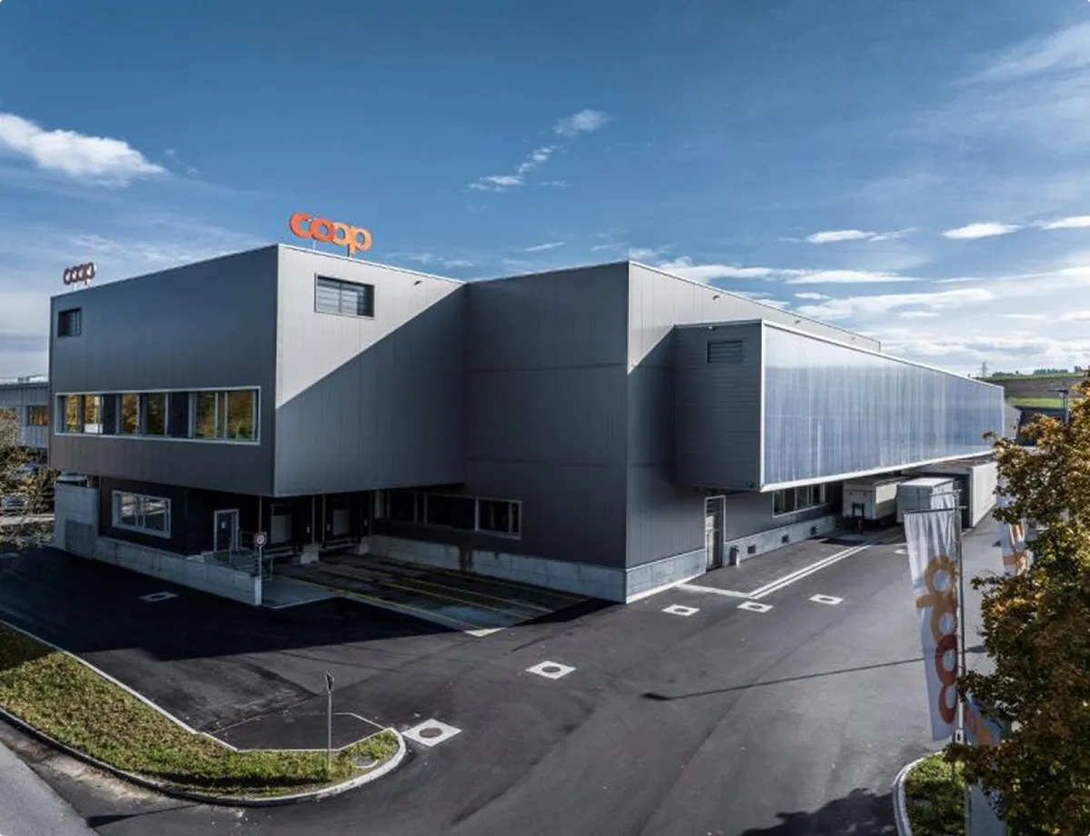 Modernes Gebäude des Coop-Logistikzentrums mit einem klaren blauen Himmel im Hintergrund.