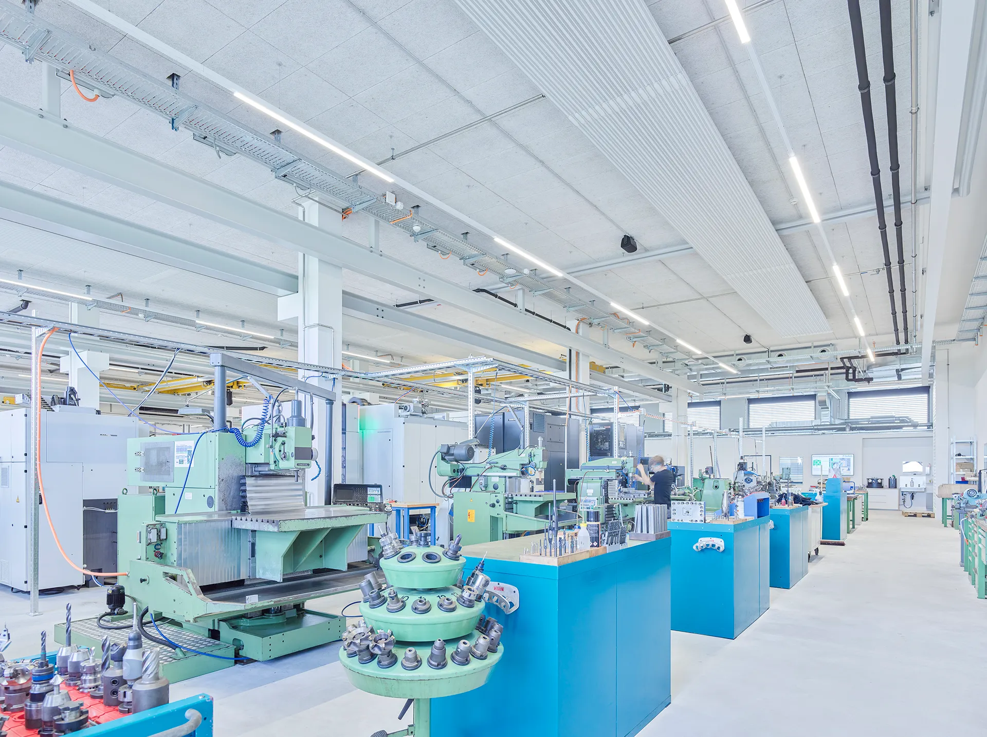 Helle, moderne Produktionshalle mit industriellen Werkzeugmaschinen und automatisierter Fertigungstechnik für präzise, effiziente Produktionsprozesse.