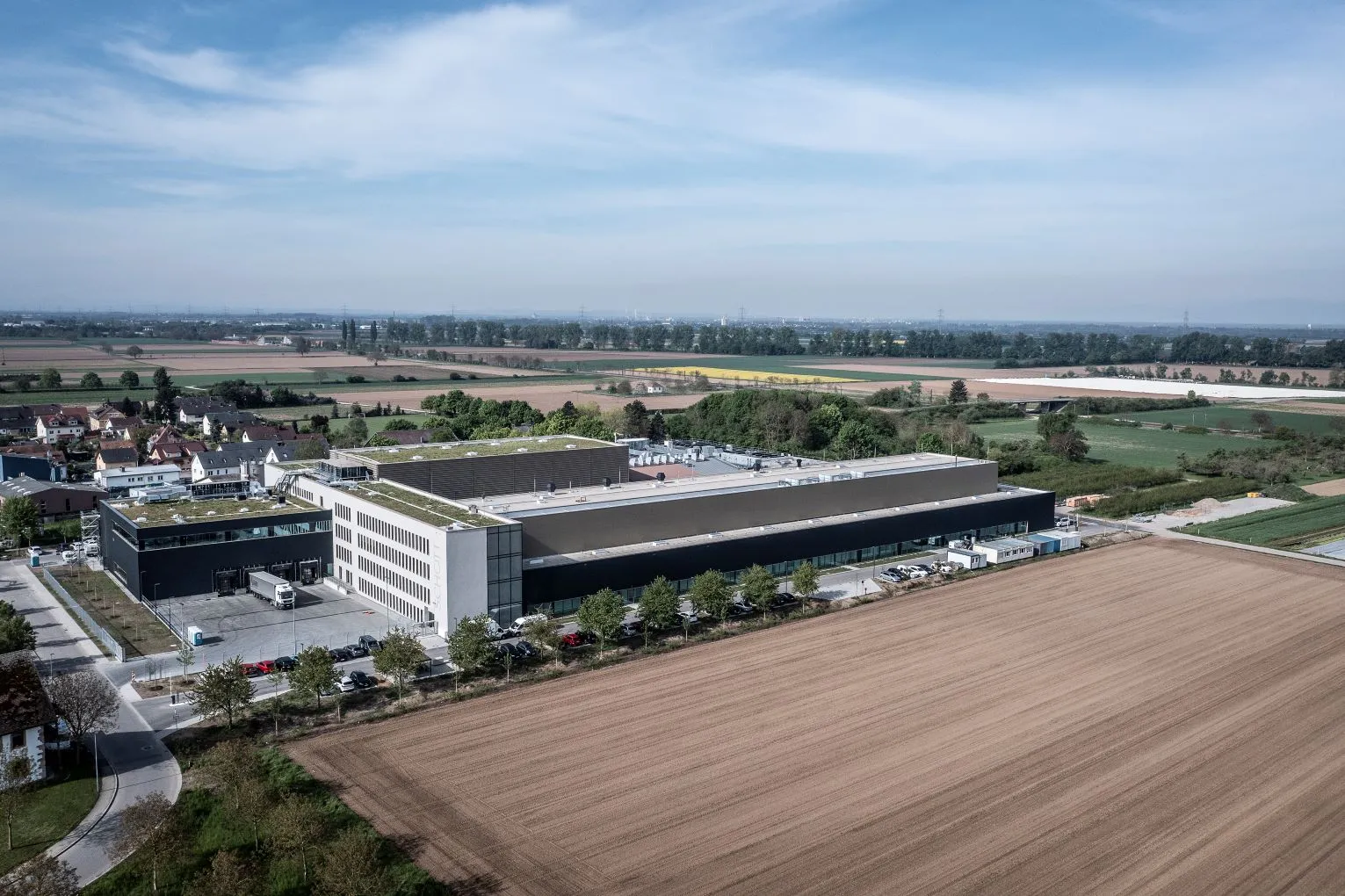 A modern industrial building in the midst of an extensive landscape, whose efficient site planning and sustainable architecture enable optimal production and logistics processes.