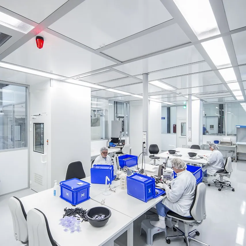 A modern, risk-based clean room with several workplaces where employees in protective clothing carry out quality-relevant manual activities to ensure controlled conditions in accordance with GMP and risk management concepts.