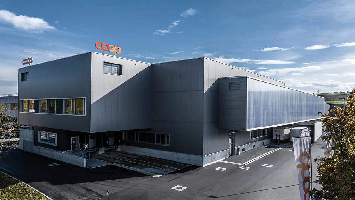 Modern coop building with grey façade under blue sky.