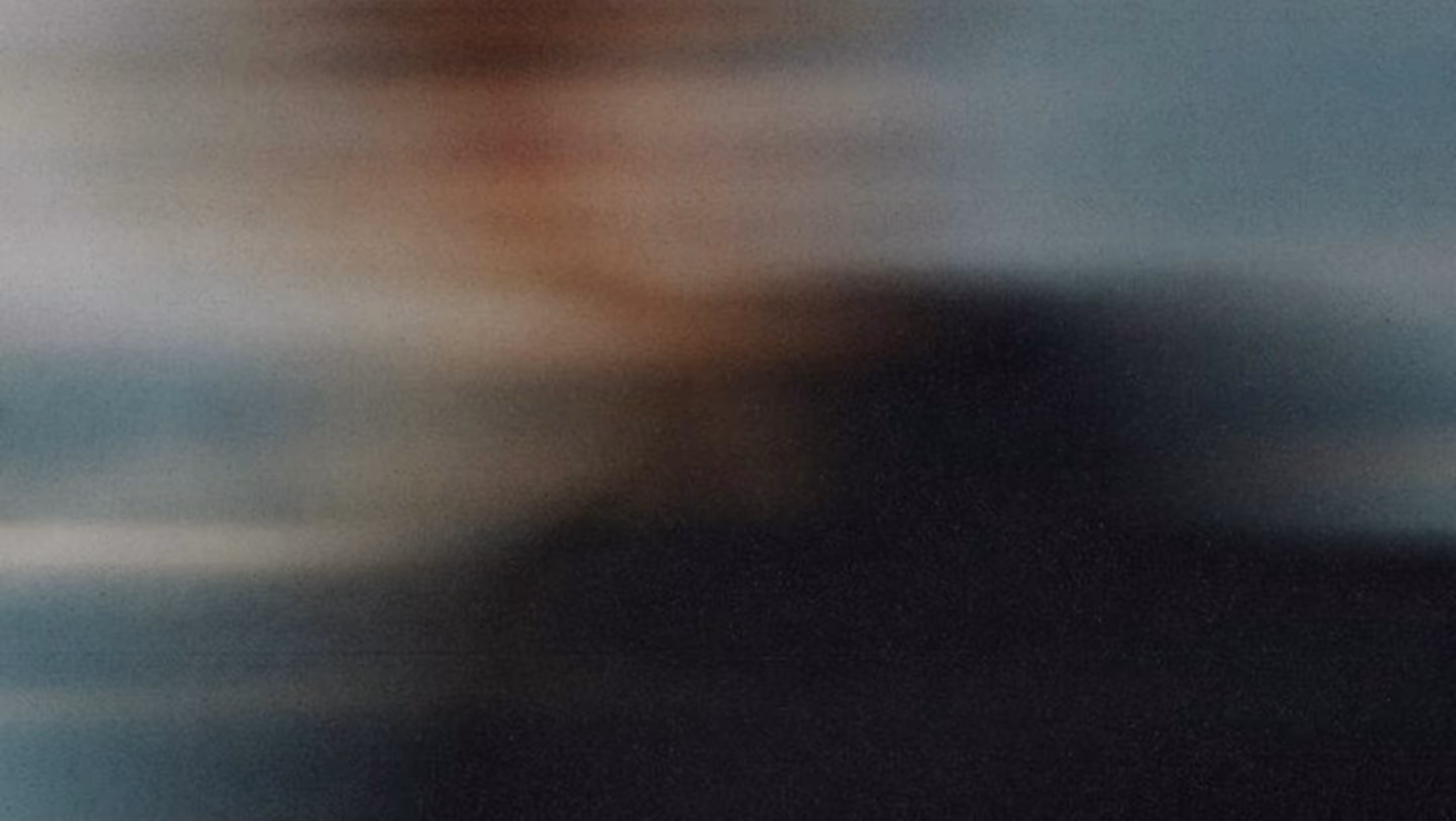 Abstract blurred gradient of dark blue, black, and light brown tones blending softly.