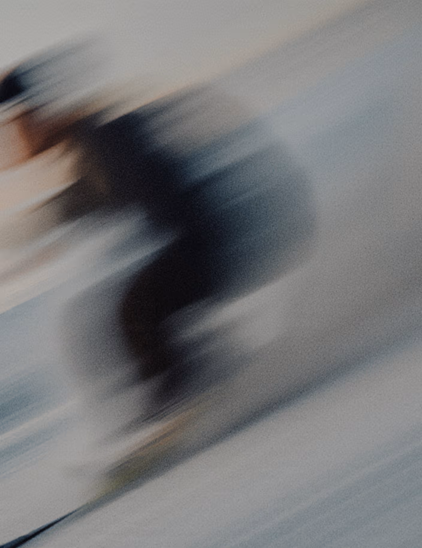 Blurry image of a person in dark clothing skiing downhill at speed.