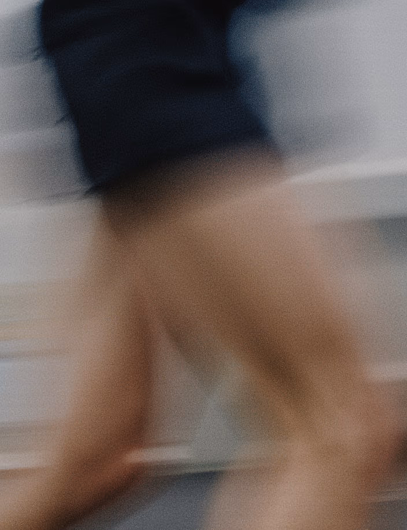 Blurred motion of a person running indoors wearing a dark top and shorts.