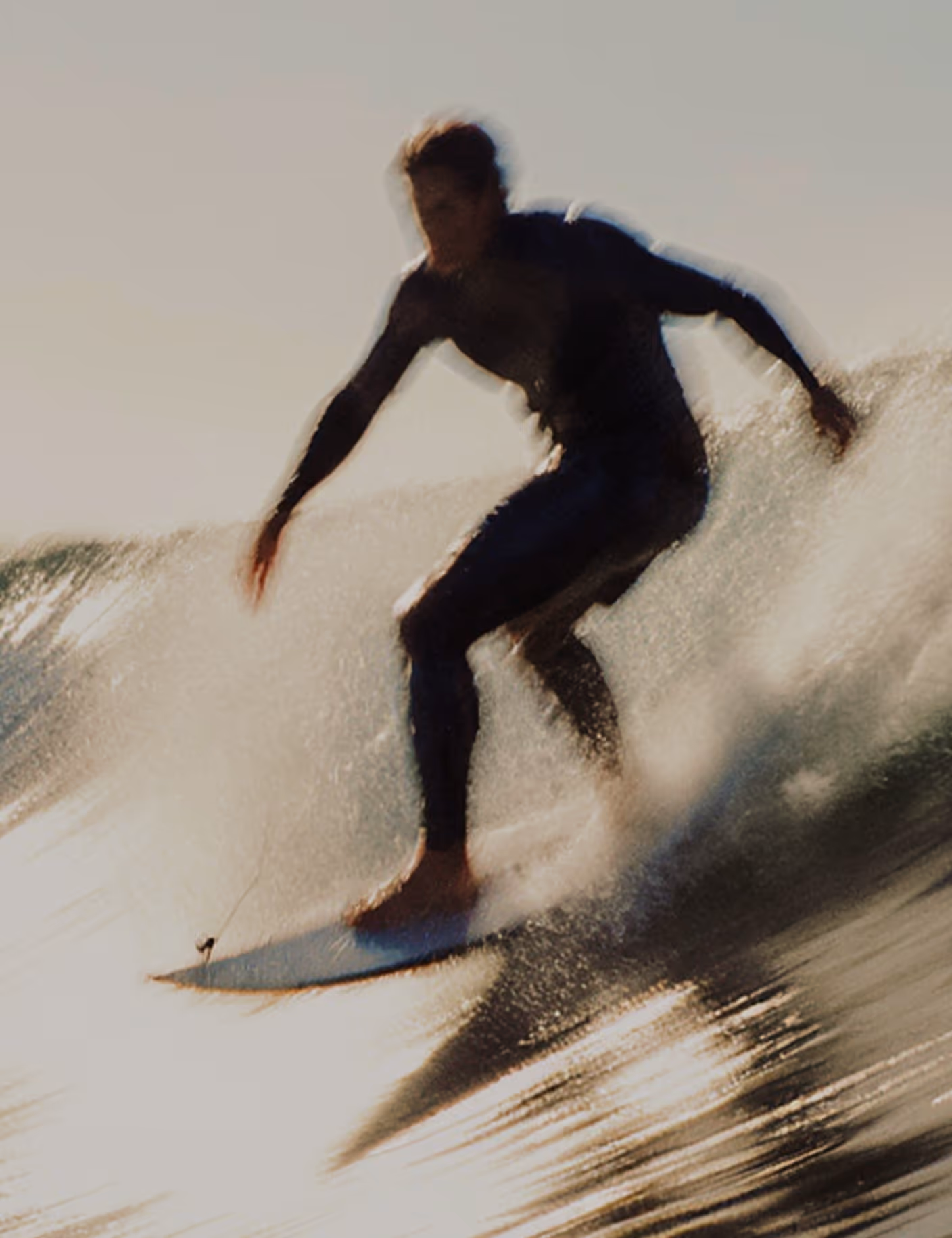 Surfer in a black wetsuit riding a wave with water splashing around.