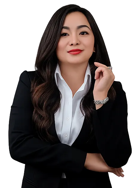 Confident woman with long dark hair wearing a black blazer and white shirt, posing with crossed arms.