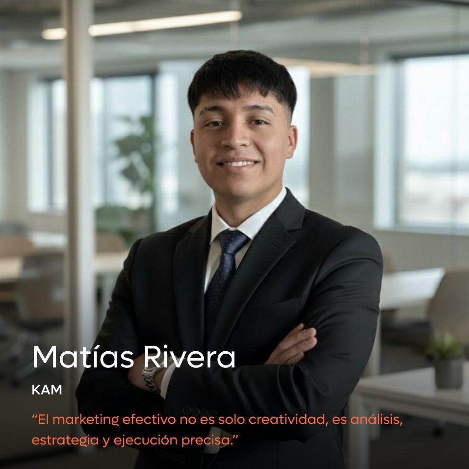 Smiling man in a black suit with arms crossed in a modern office setting.