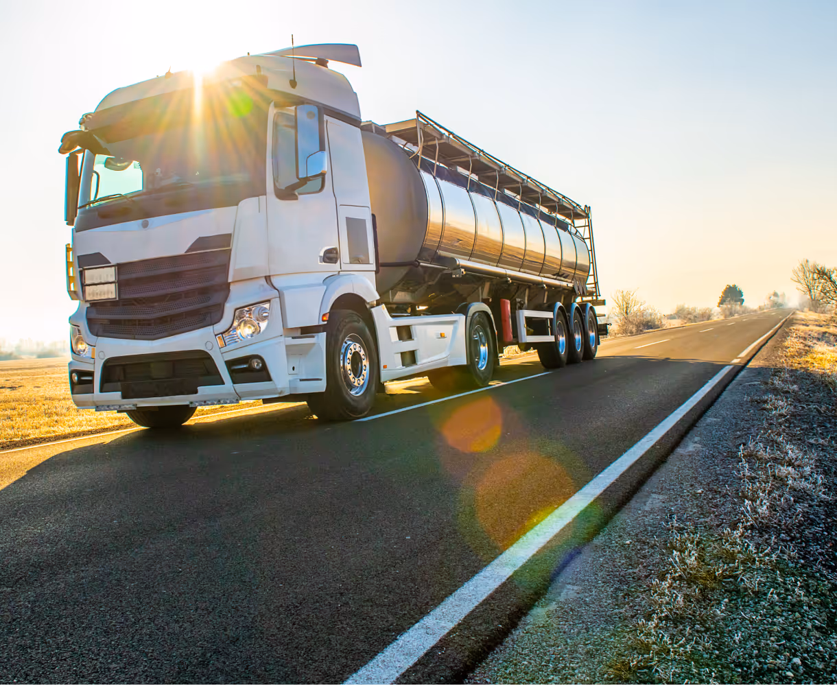 White tanker truck on the side of a sunlit road