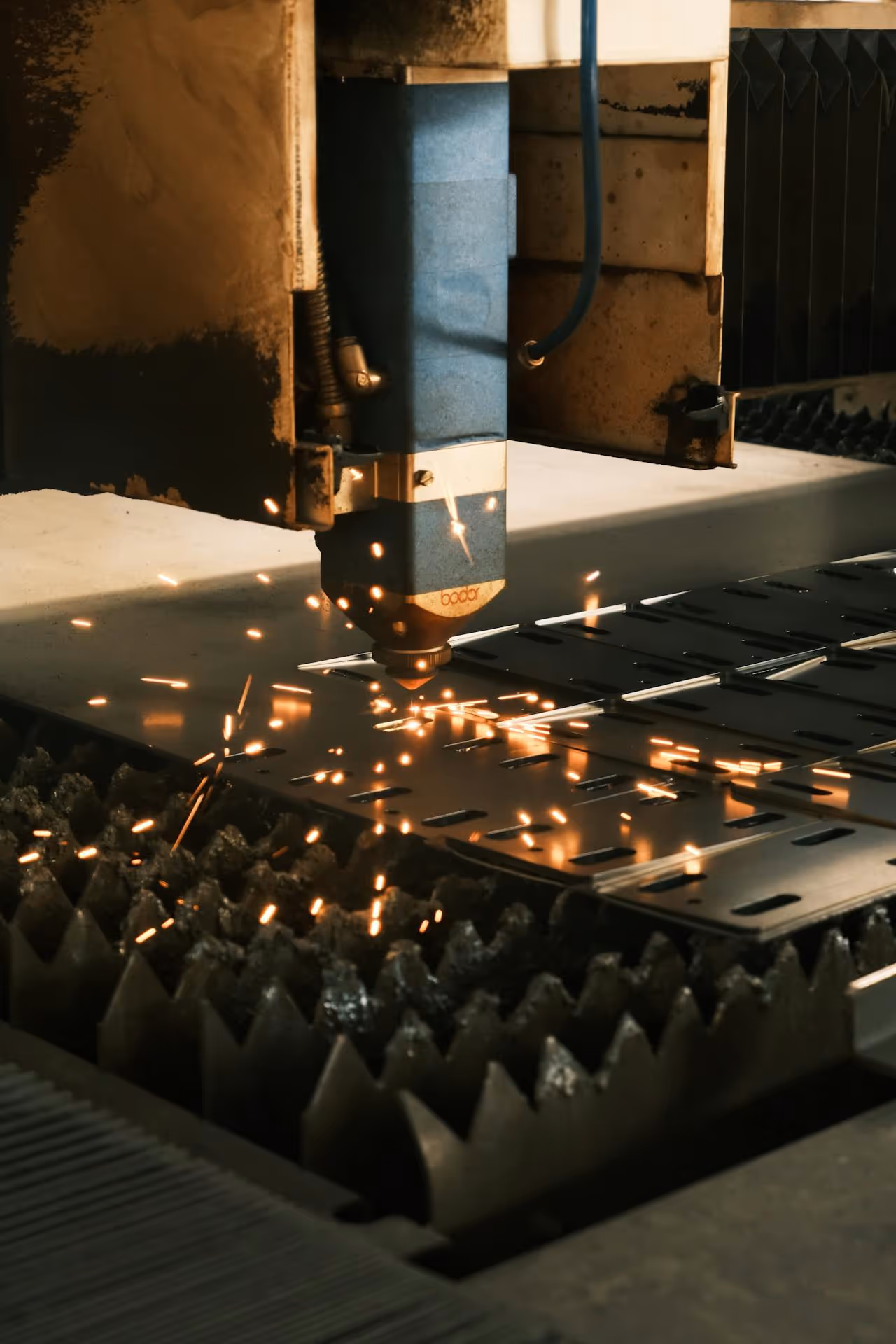 Industrial laser cutting machine creating sparks while cutting metal sheet.