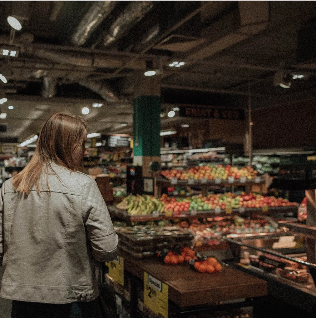A women approaching a supermarket fruit/veg stand.