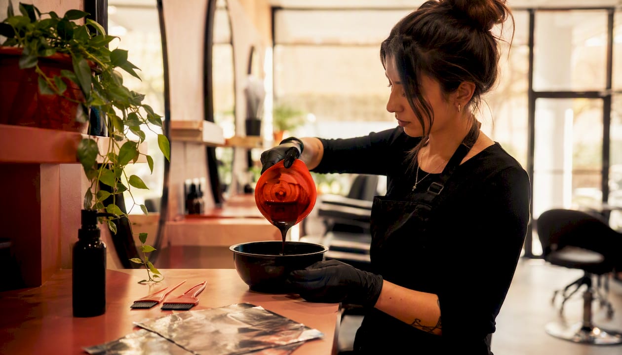 Hands pouring hair color in bowl