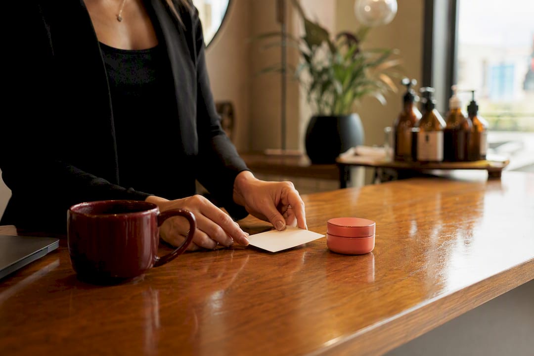 Hands preparing client rebooking materials in salon suite