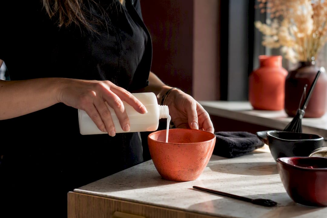 Hands mixing hair color formula in bowl