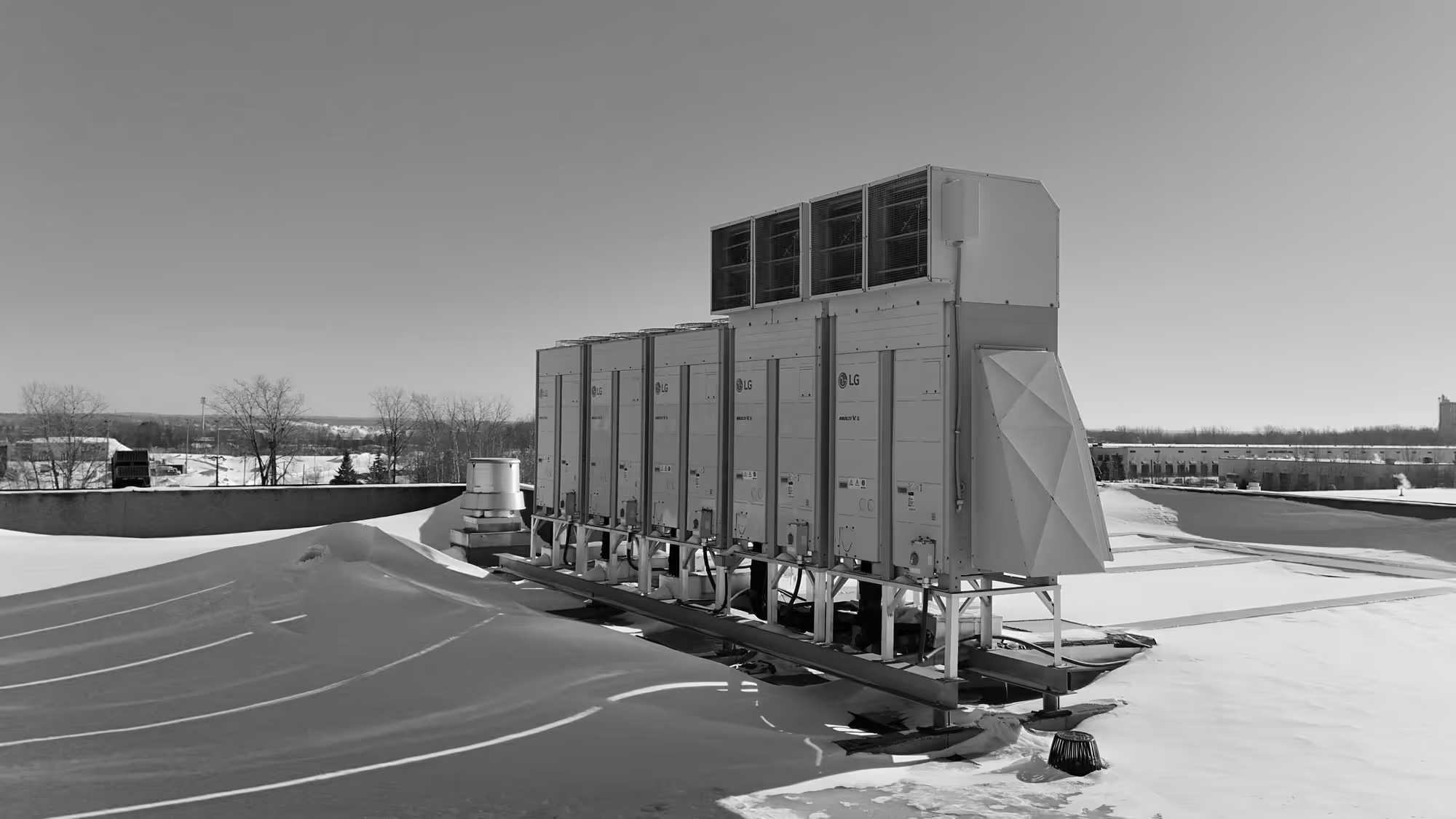 Un ensemble d'unités de climatisation LG installées sur un toit enneigé sous un ciel clair.