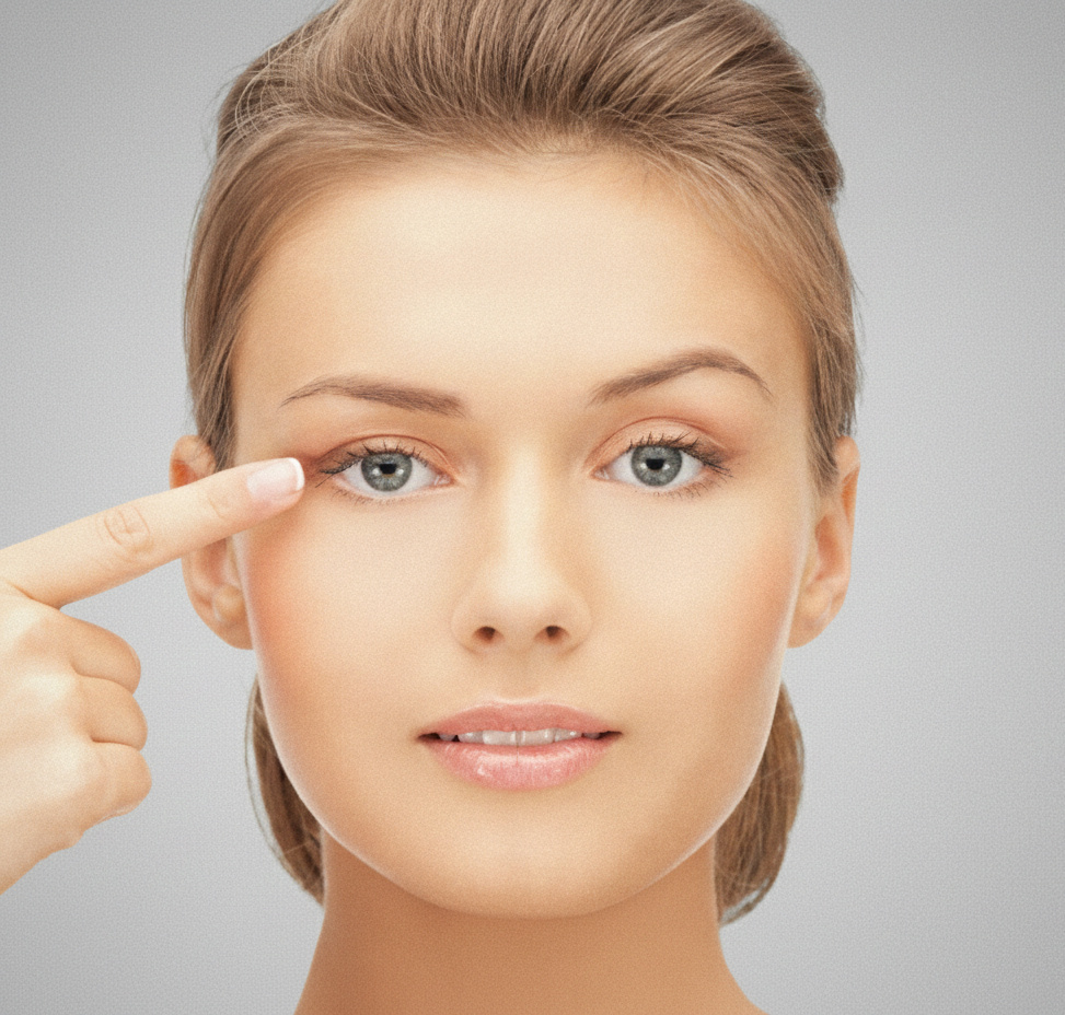 Woman pointing to her right eye with her index finger on a neutral background.