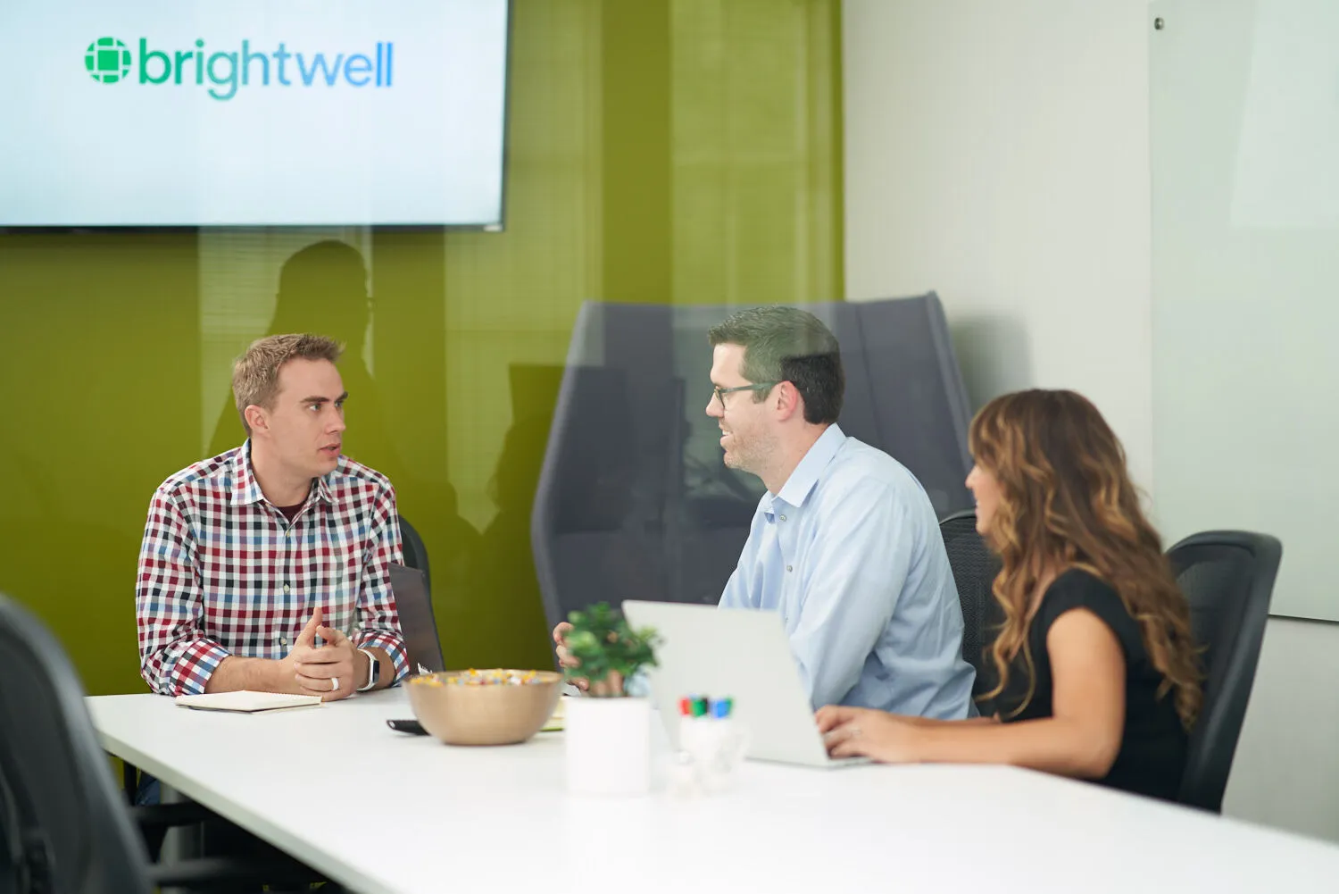 Two men and a woman sitting at a table talking.