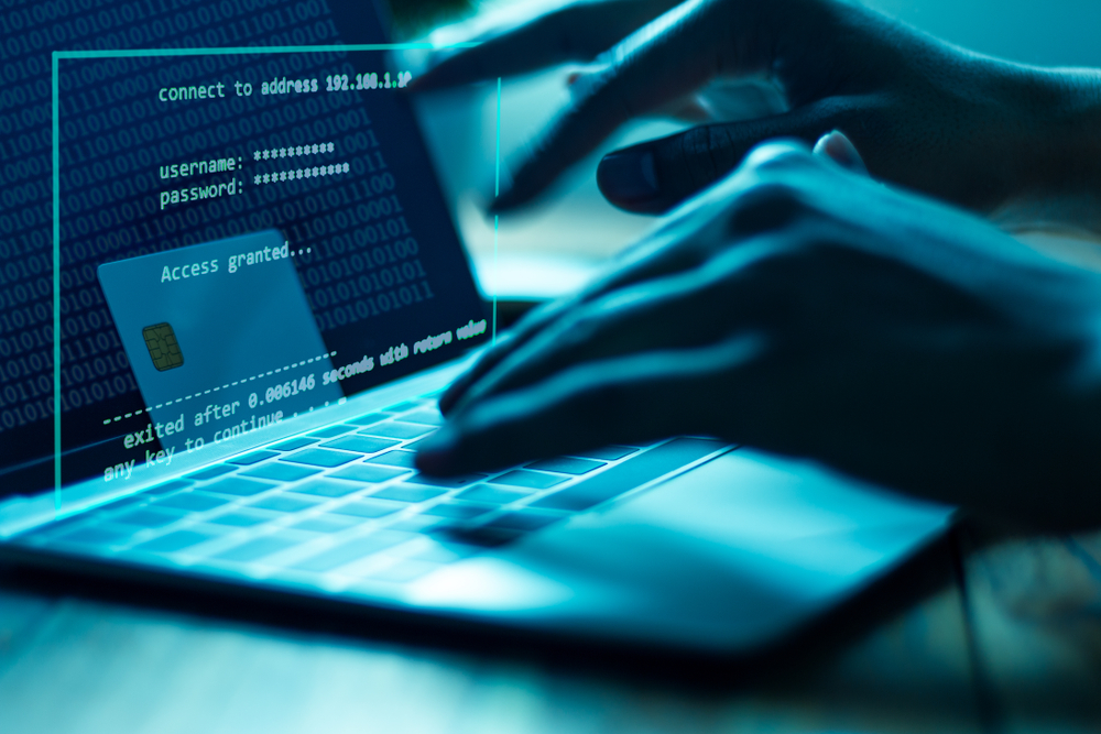 A person sits in a dark room at a computer, typing in a password. Brightwell monitors every transaction sent through its payment products to protect consumers from card fraud.