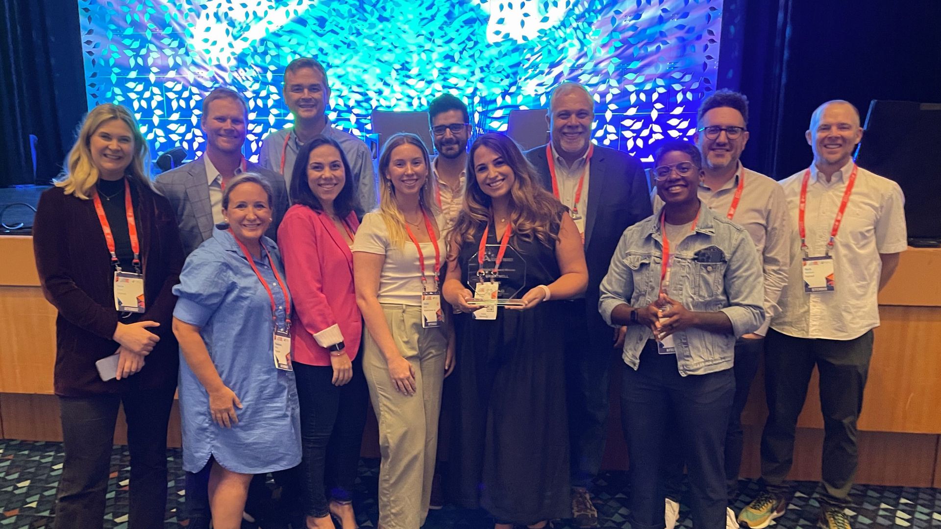 A group of Brightwell employees stand in front of the stage at FinTech South proudly displaying their FinTech Advance Award.