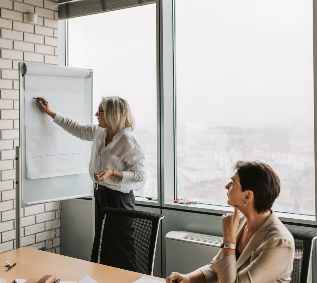 Woman is righting in white board and explaining