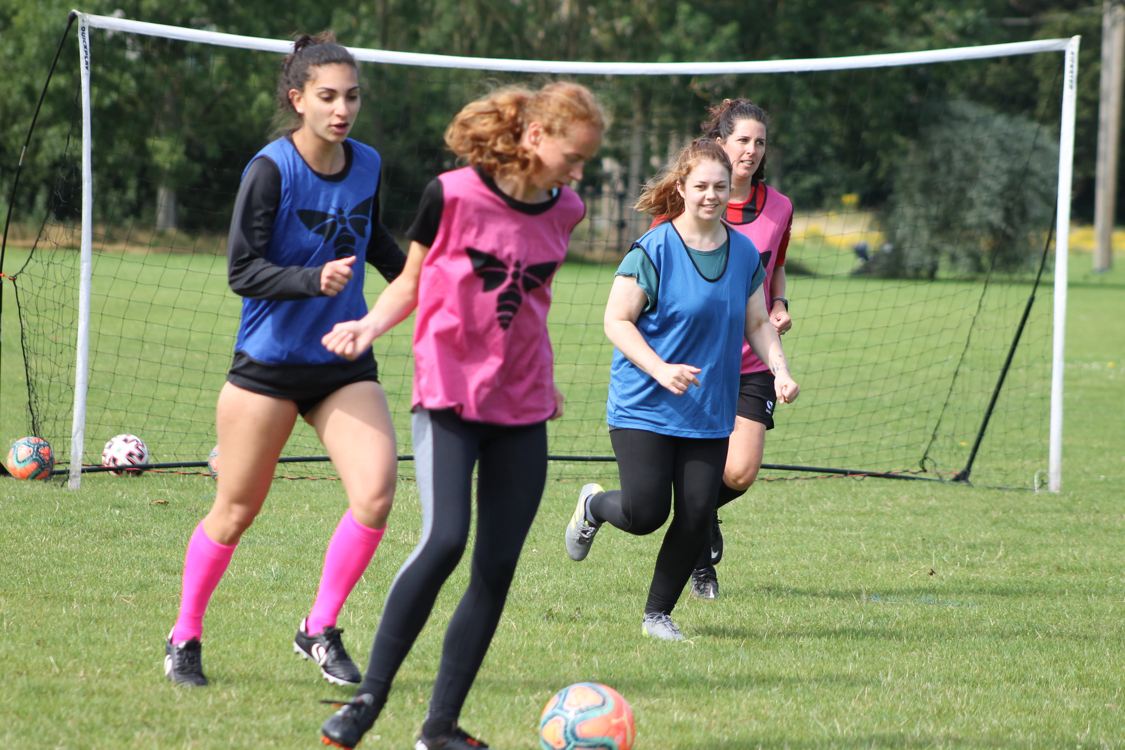 Four women playing football on a field.