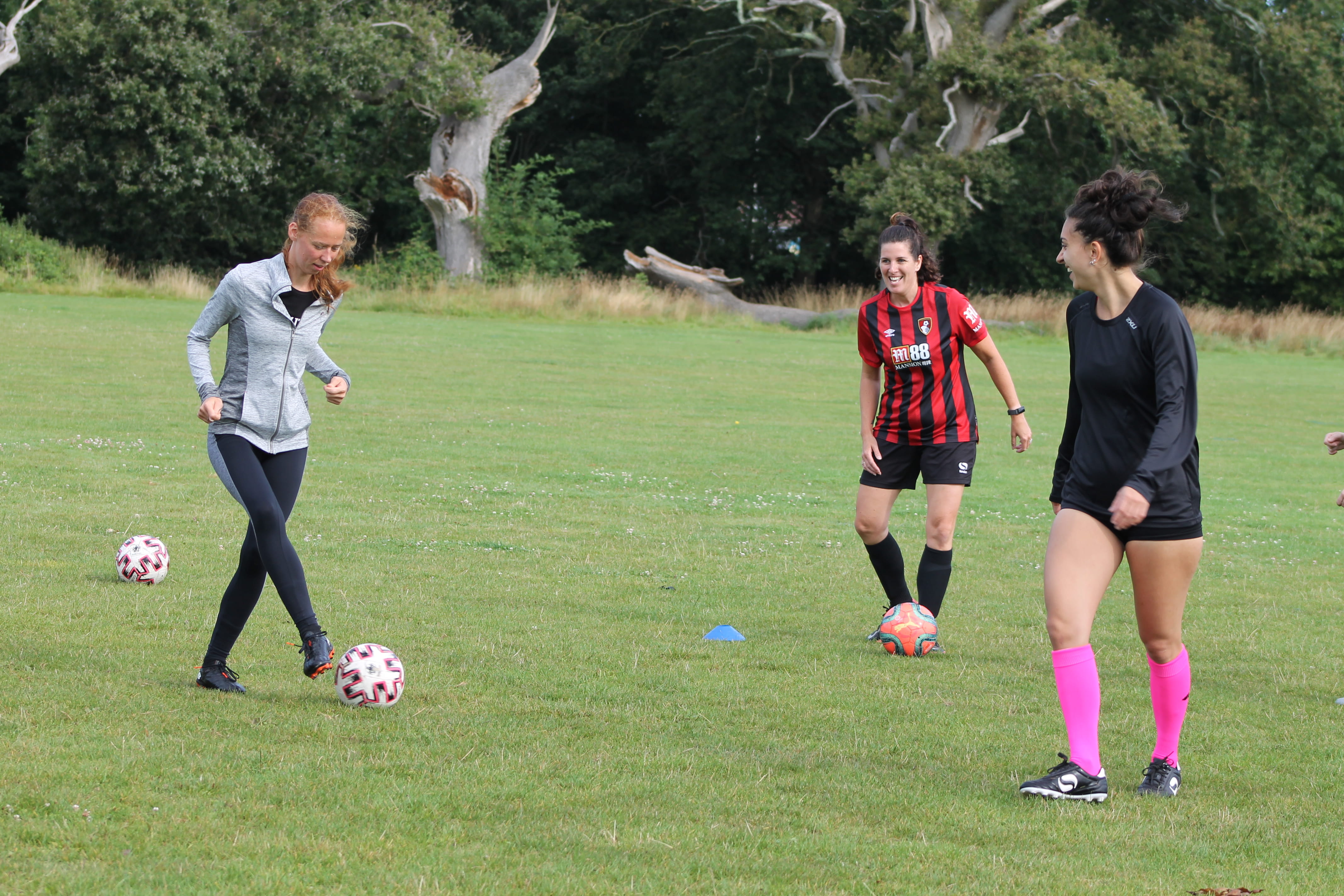 Three women playing football on a field.