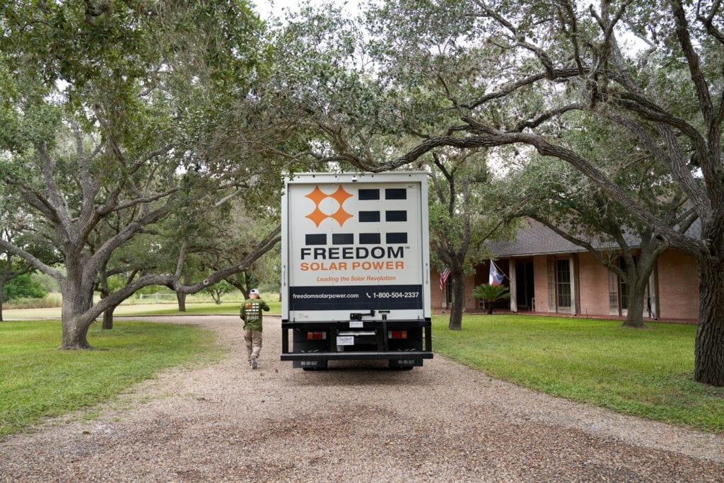 white box truck driving on gravel road under Texas mesquite trees