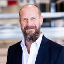 Headshot for Freedom Solar Power CEO, Bret Biggart, smiling in a white shirt and dark jacket.