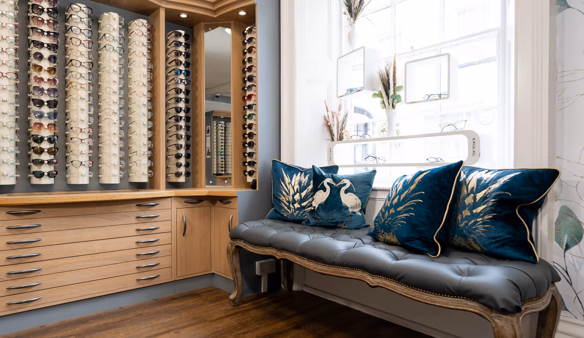 Comfortable seating area with decorative cushions and eyewear display cabinets