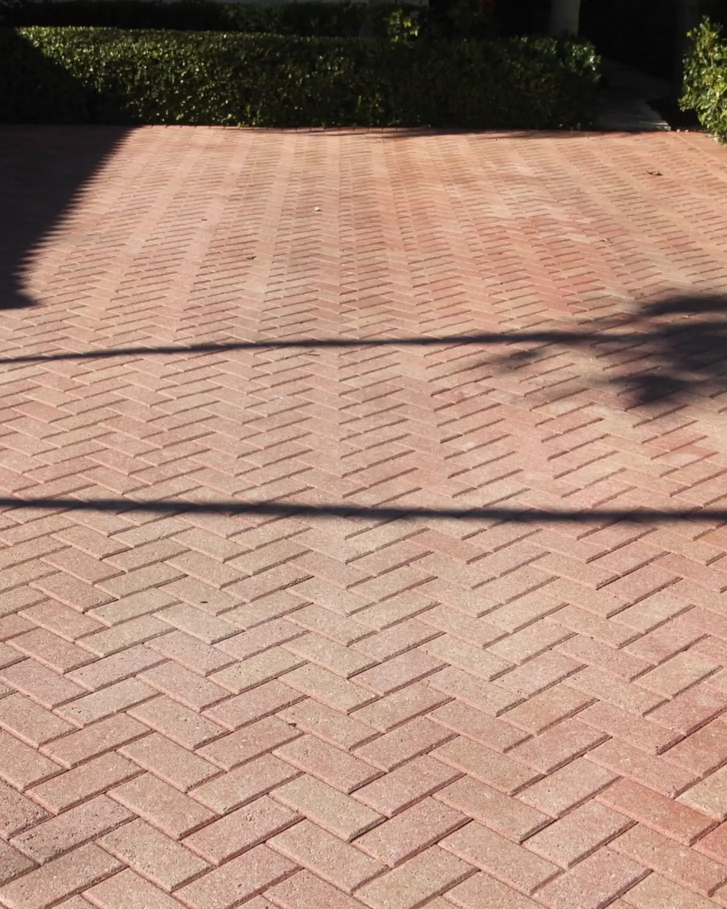 Close-up of a paved stone driveway with a curved border and a grassy area on the left side.