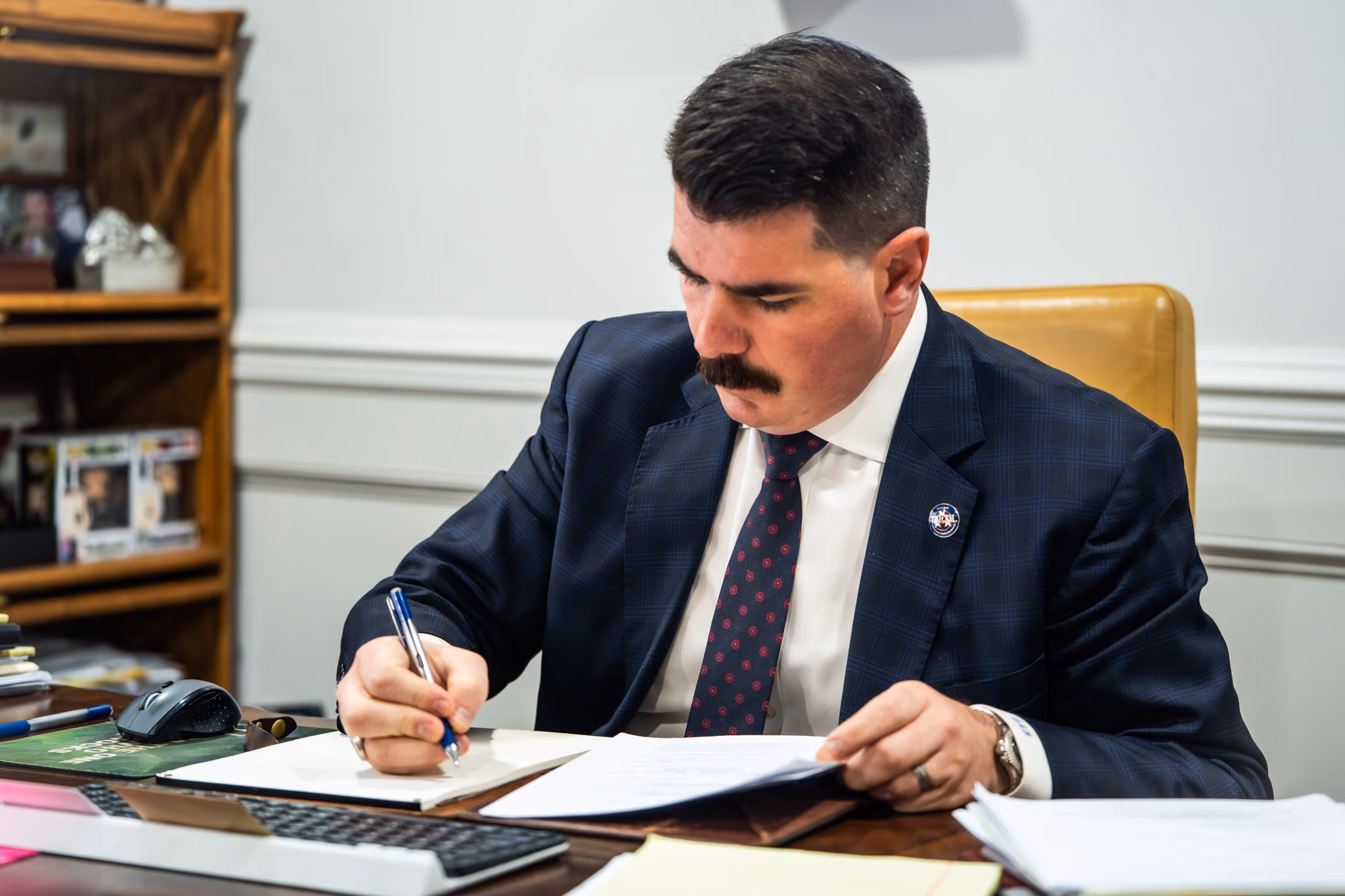 Gordon Byars sitting at his desk working and writing on the paper in front of him.