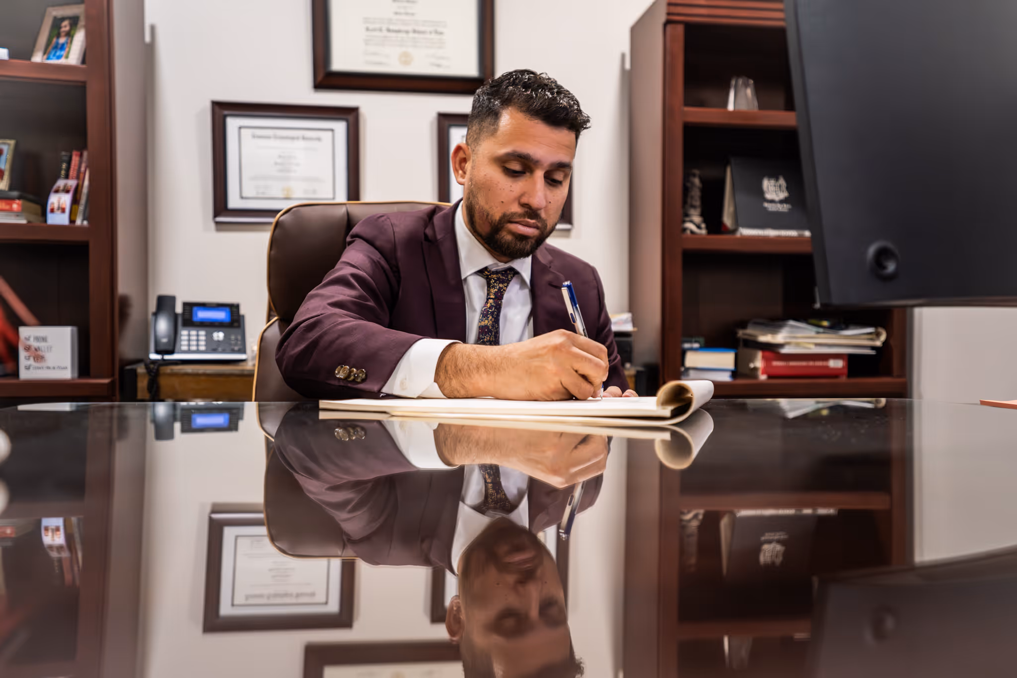 Ramon Damas sitting at his desk working and writing on the paper in front of him.