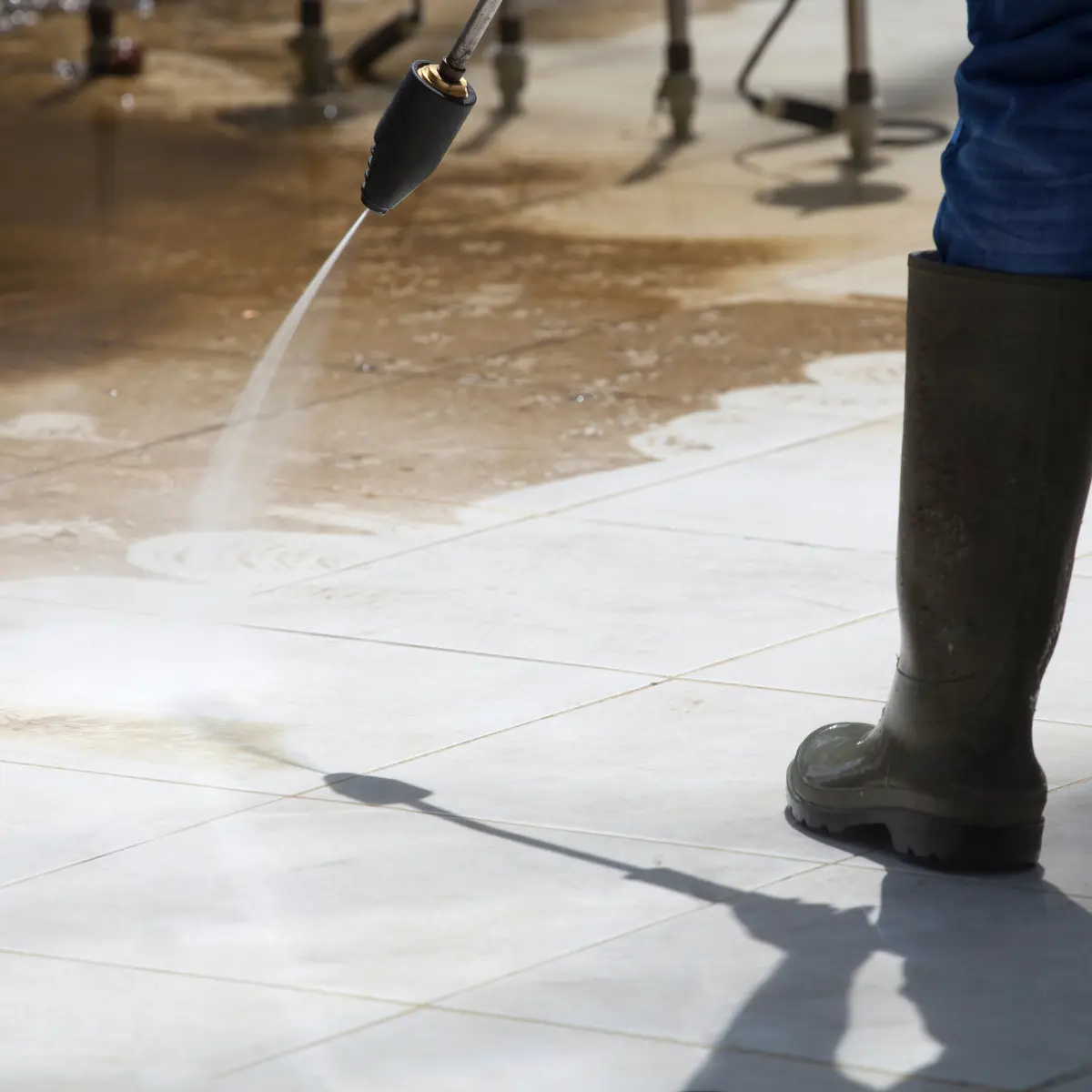 Electric floor cleaning machine scrubbing a wet tiled floor with soap suds around.