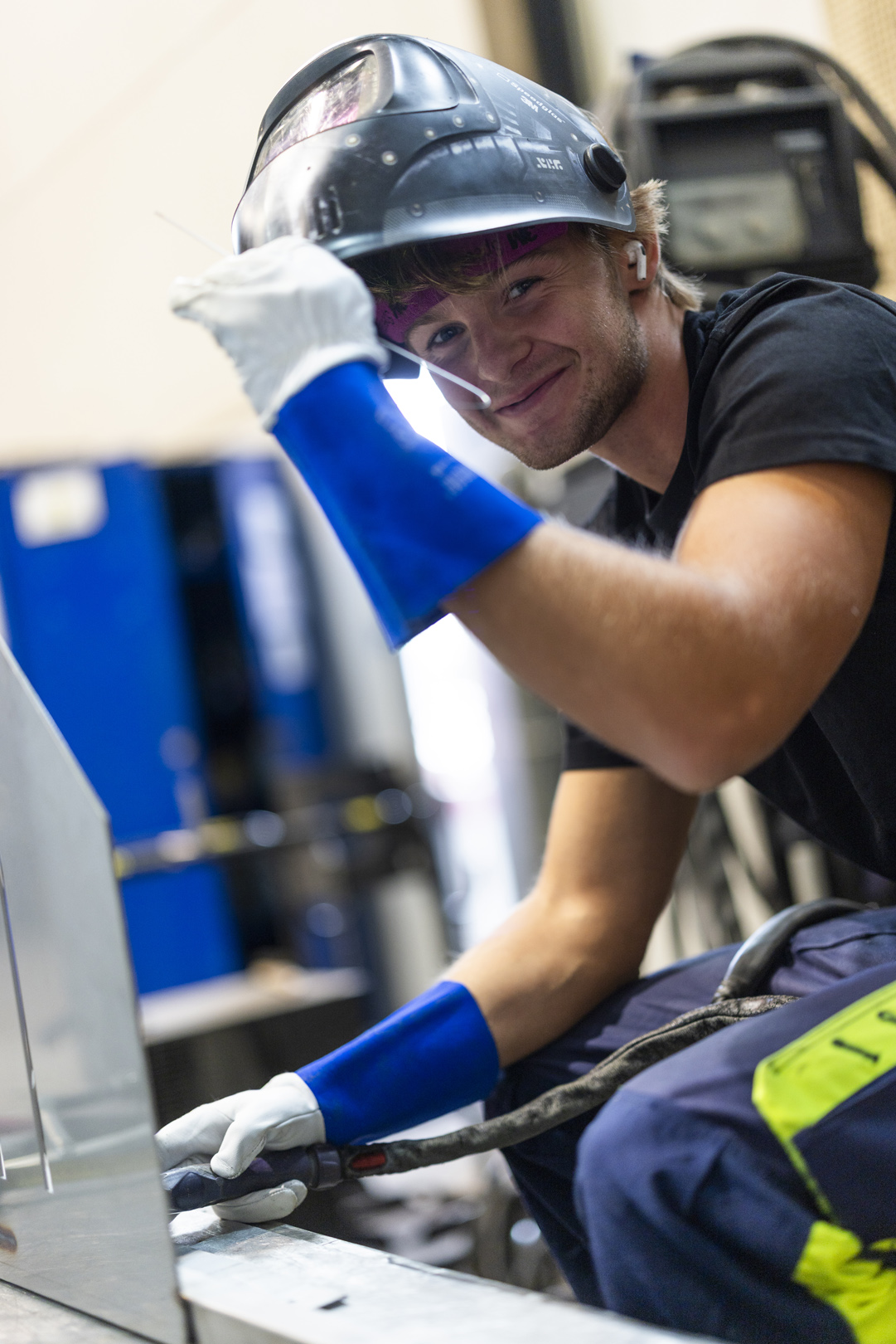 Sveiser løfter sveiseskjermen ved arbeidsbenken