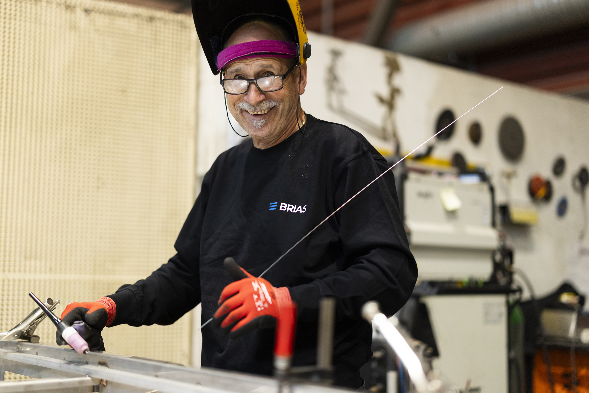 Sveiser med oppslått sveiseskjerm ved arbeidsbenken