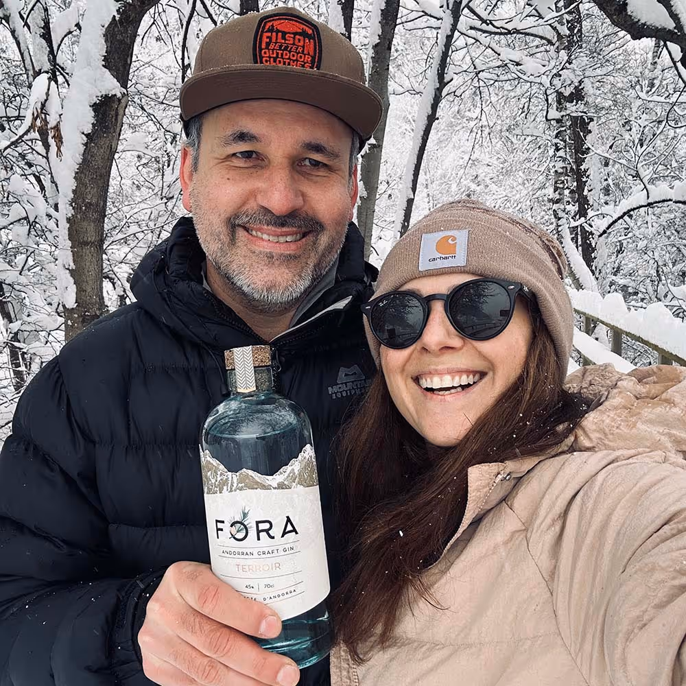 john and soraya in the snow with a bottle of fora gin
